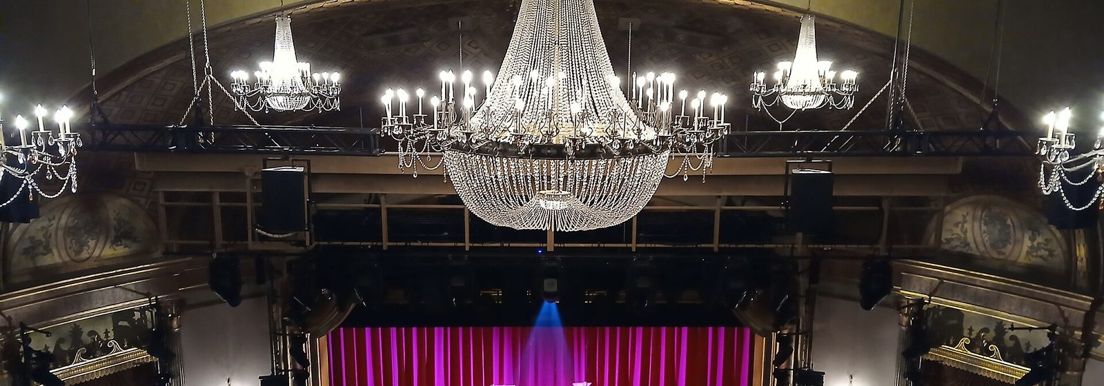 Wide balcony-level view of the auditorium of the St. James Theatre in Manhattan, New York, showing its chandeliers, domed ceiling, box seats, and stage curtain - St. James Theatre tickets